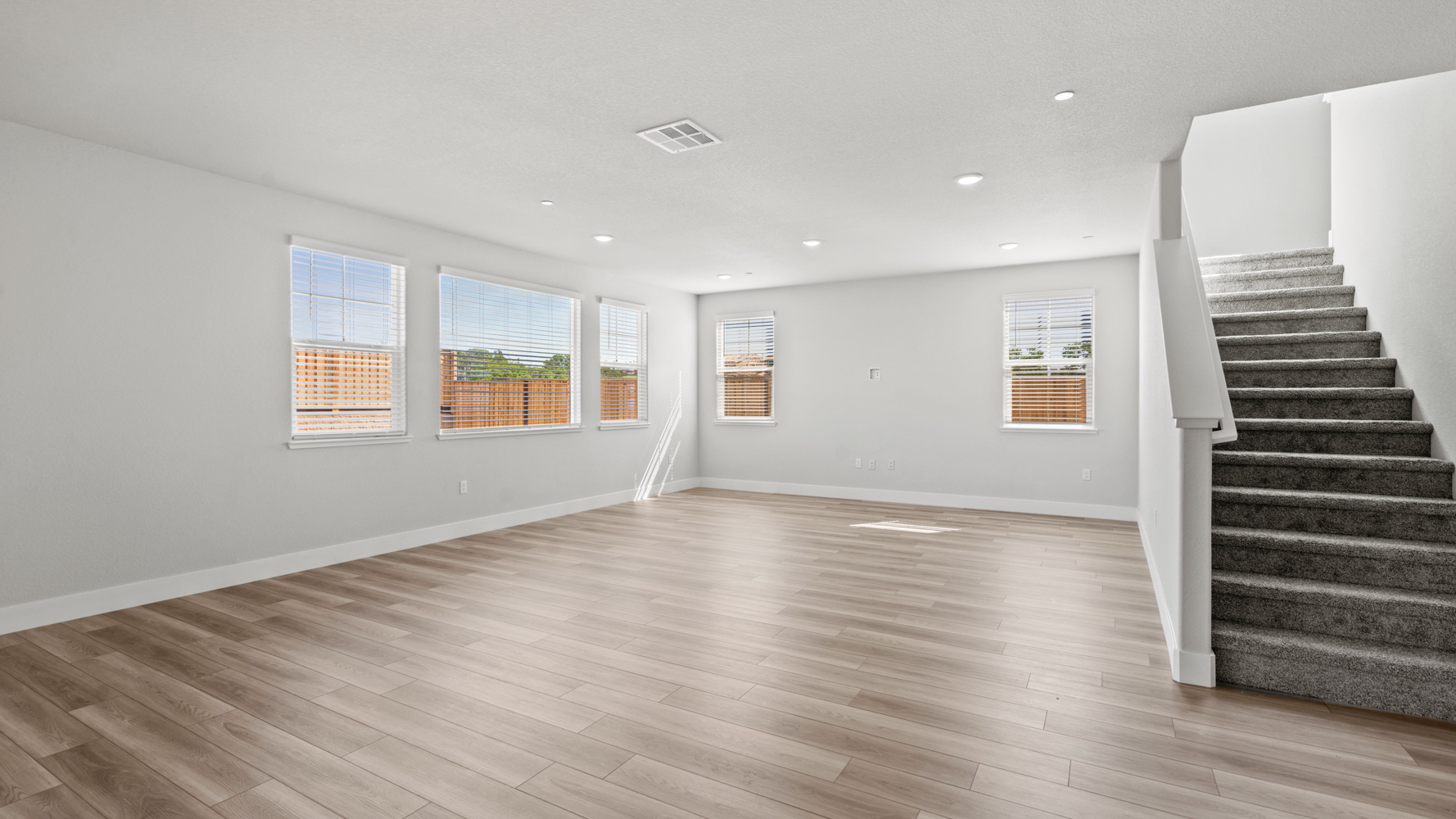 A large empty room with a wood floor and windows.