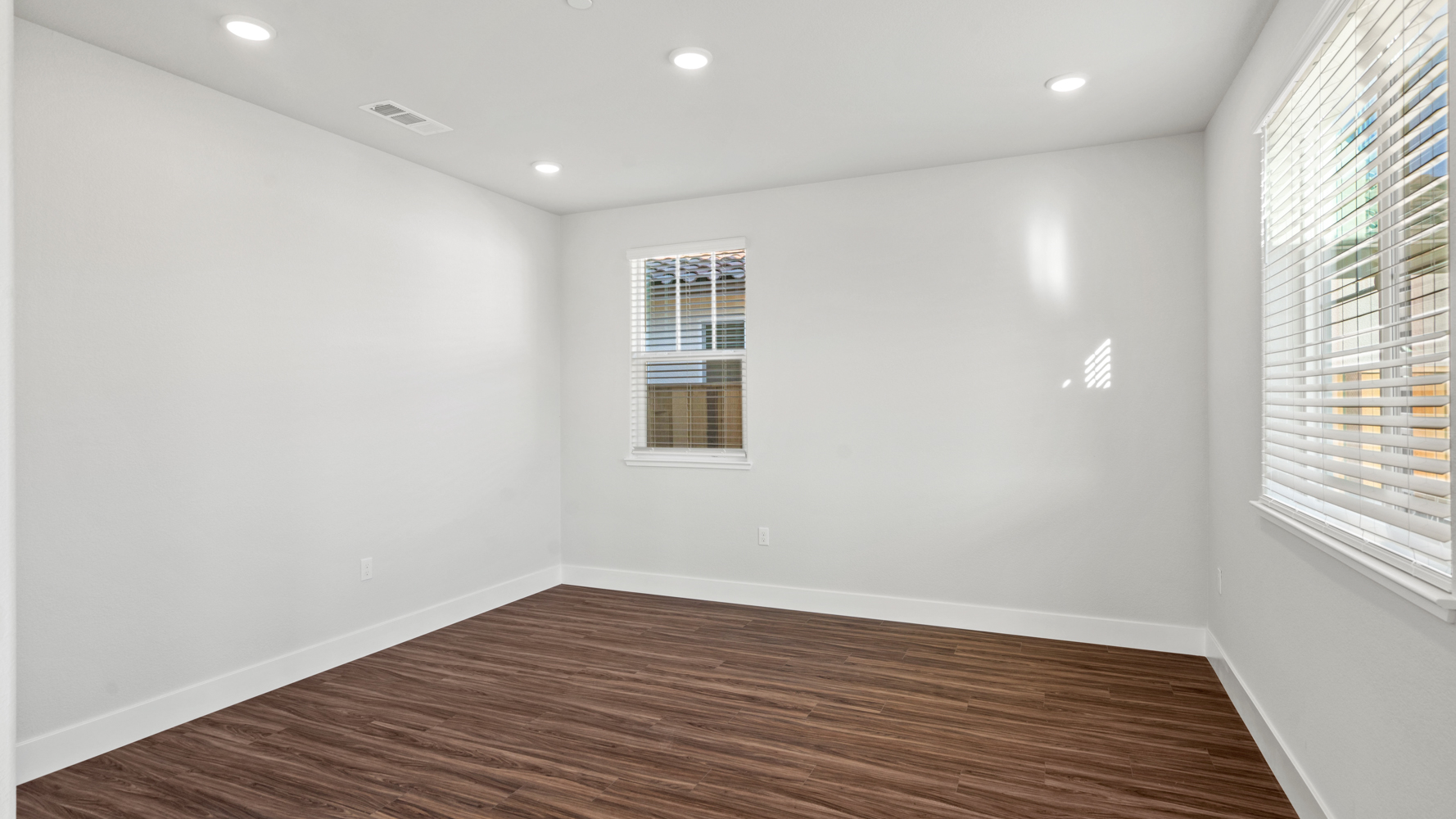 A room with a wood floor and windows.
