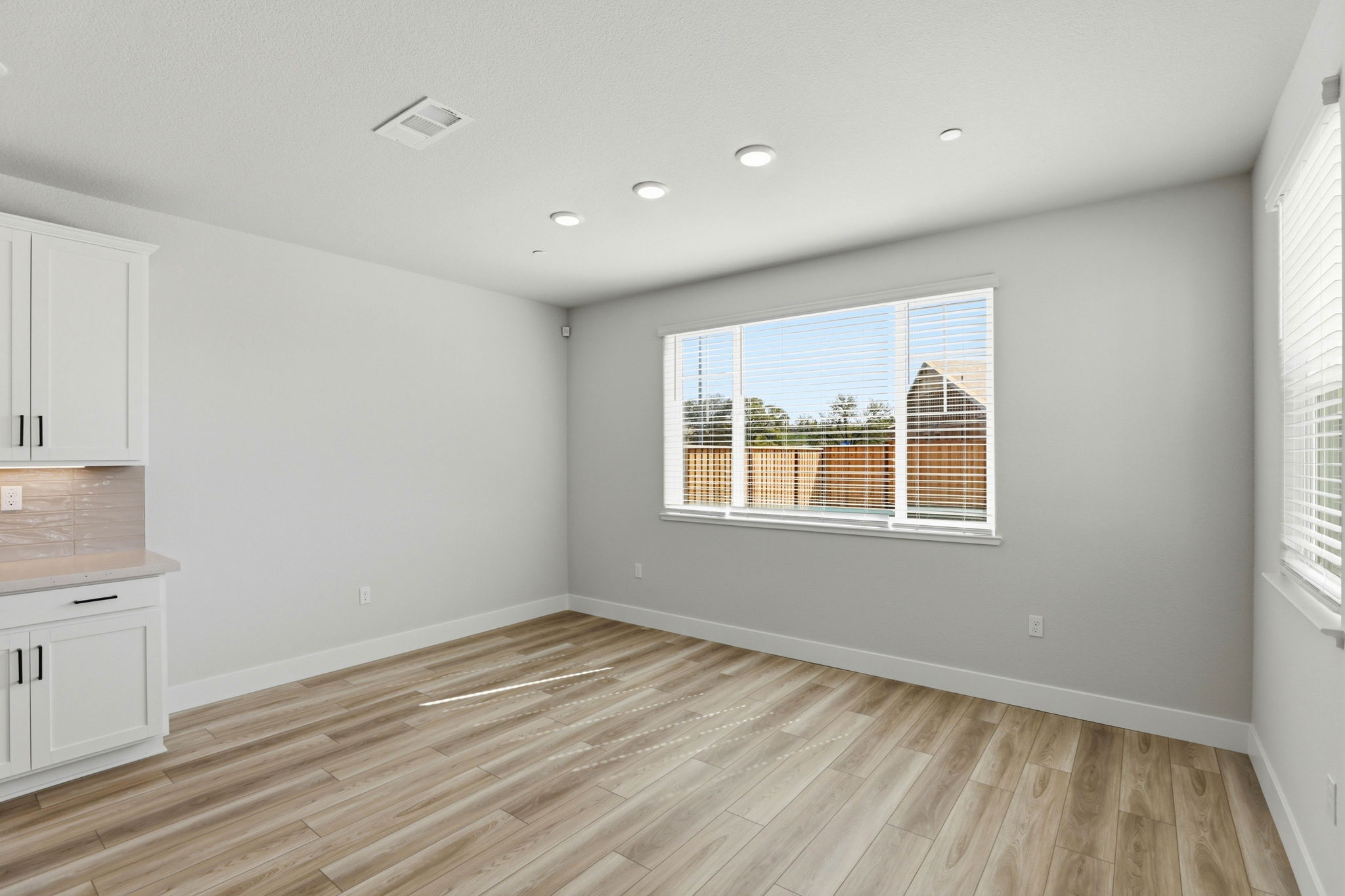 A room with a wood floor and a window with blinds.