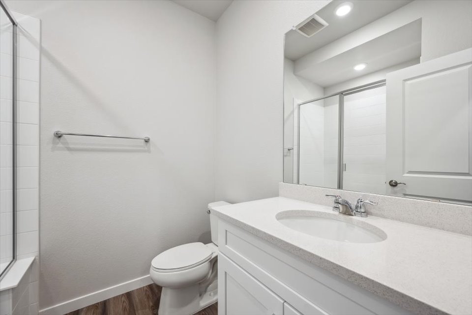 A bathroom with a sink toilet and mirror.