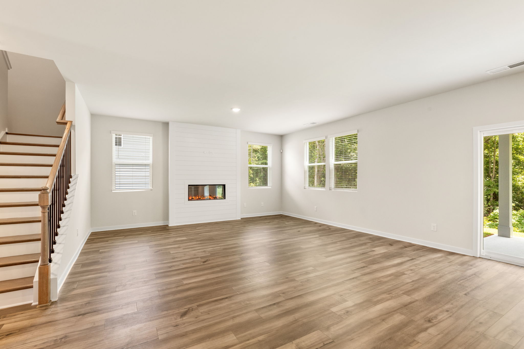 A room with a wood floor and a wood staircase.