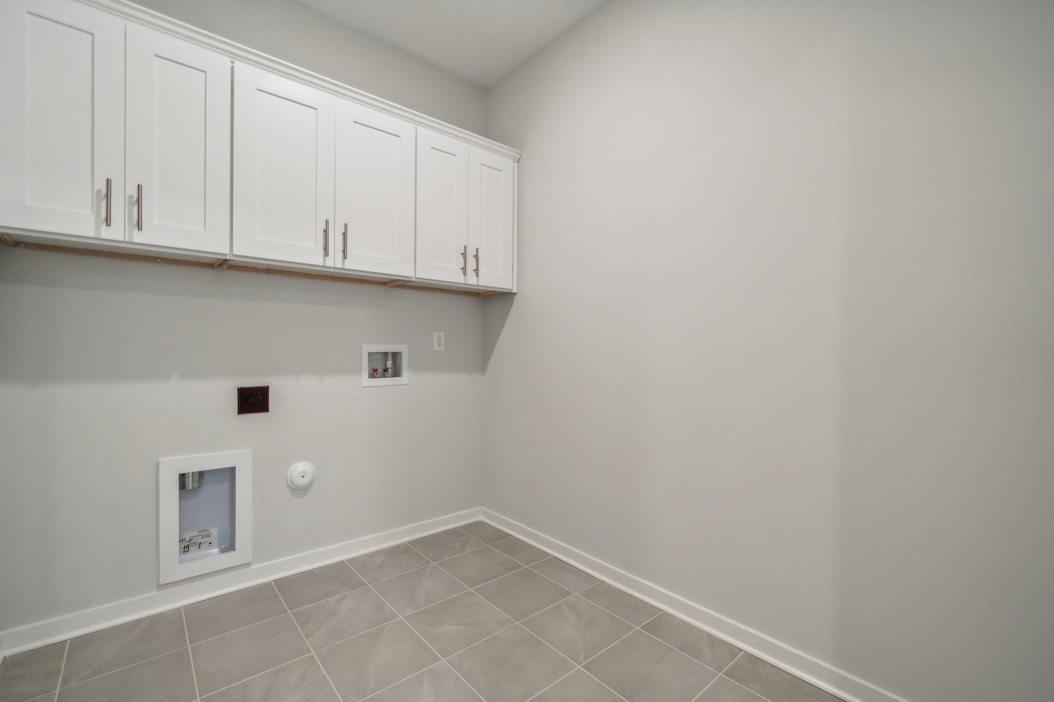 A white wall with white cabinets.