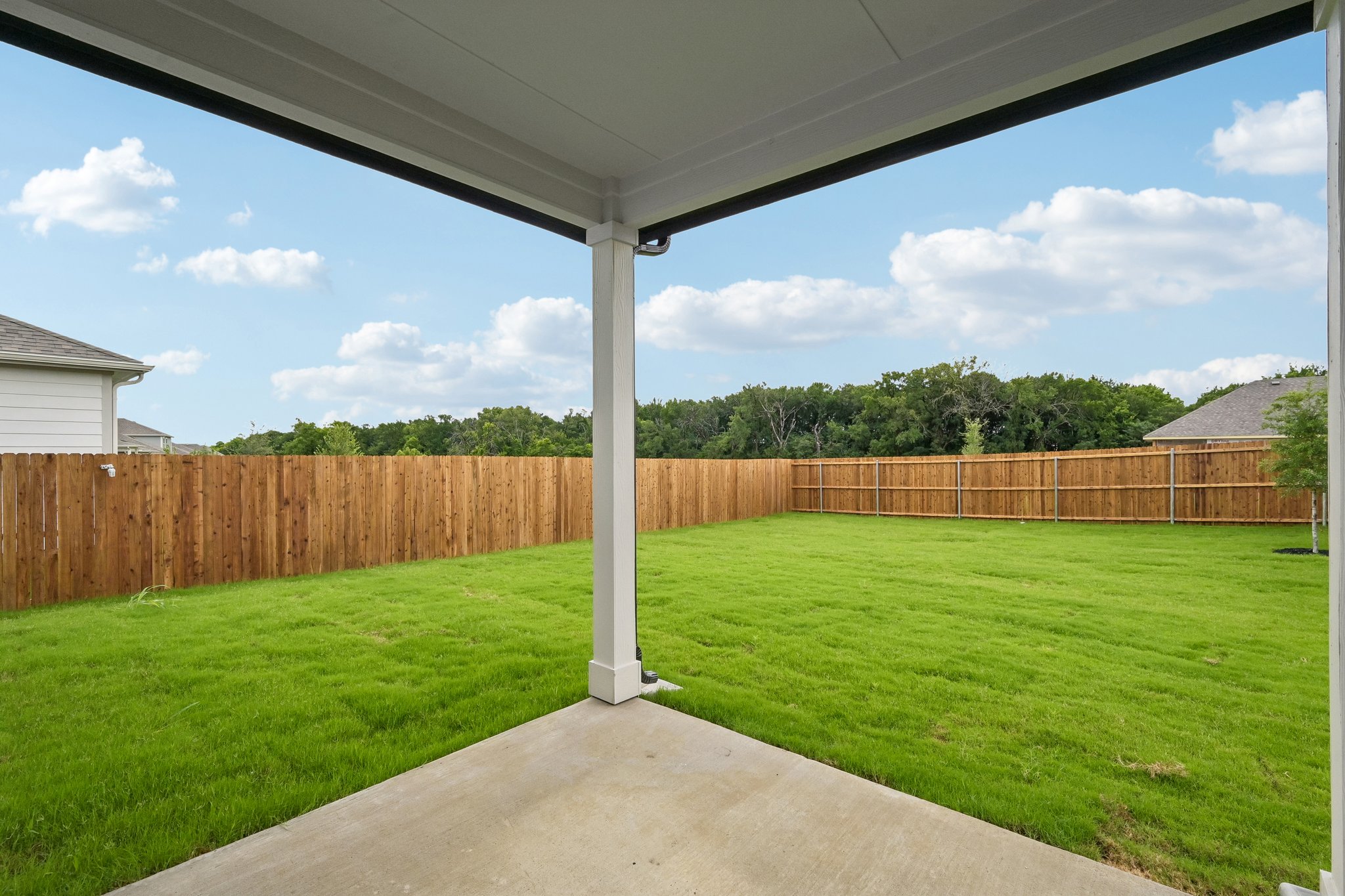 A backyard with a fence and a walkway.