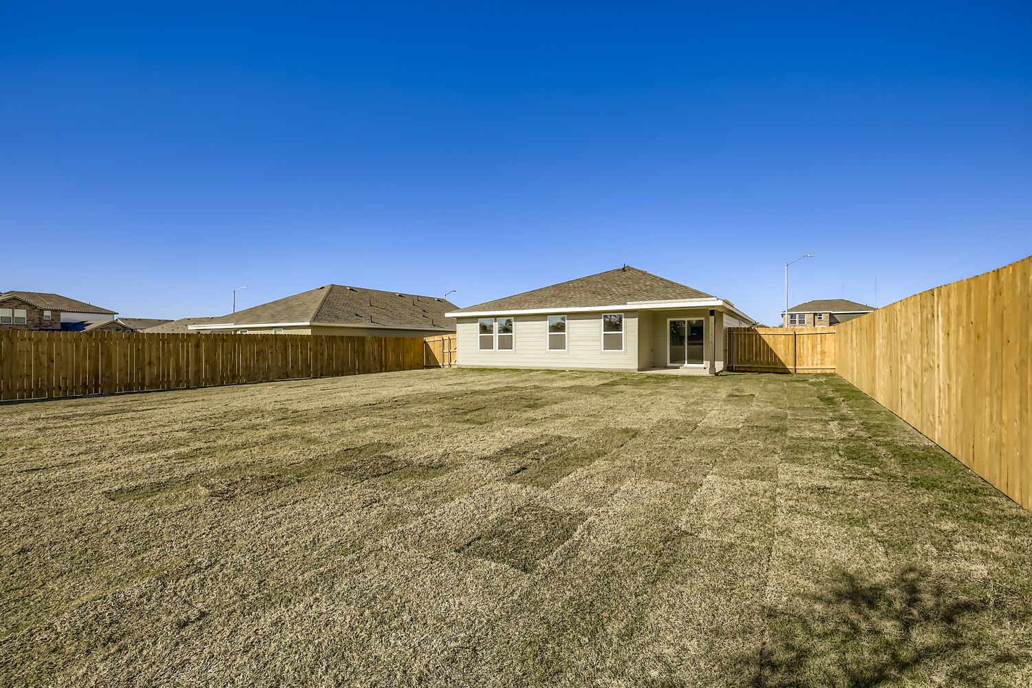 A dirt field with a fence and buildings in the background.