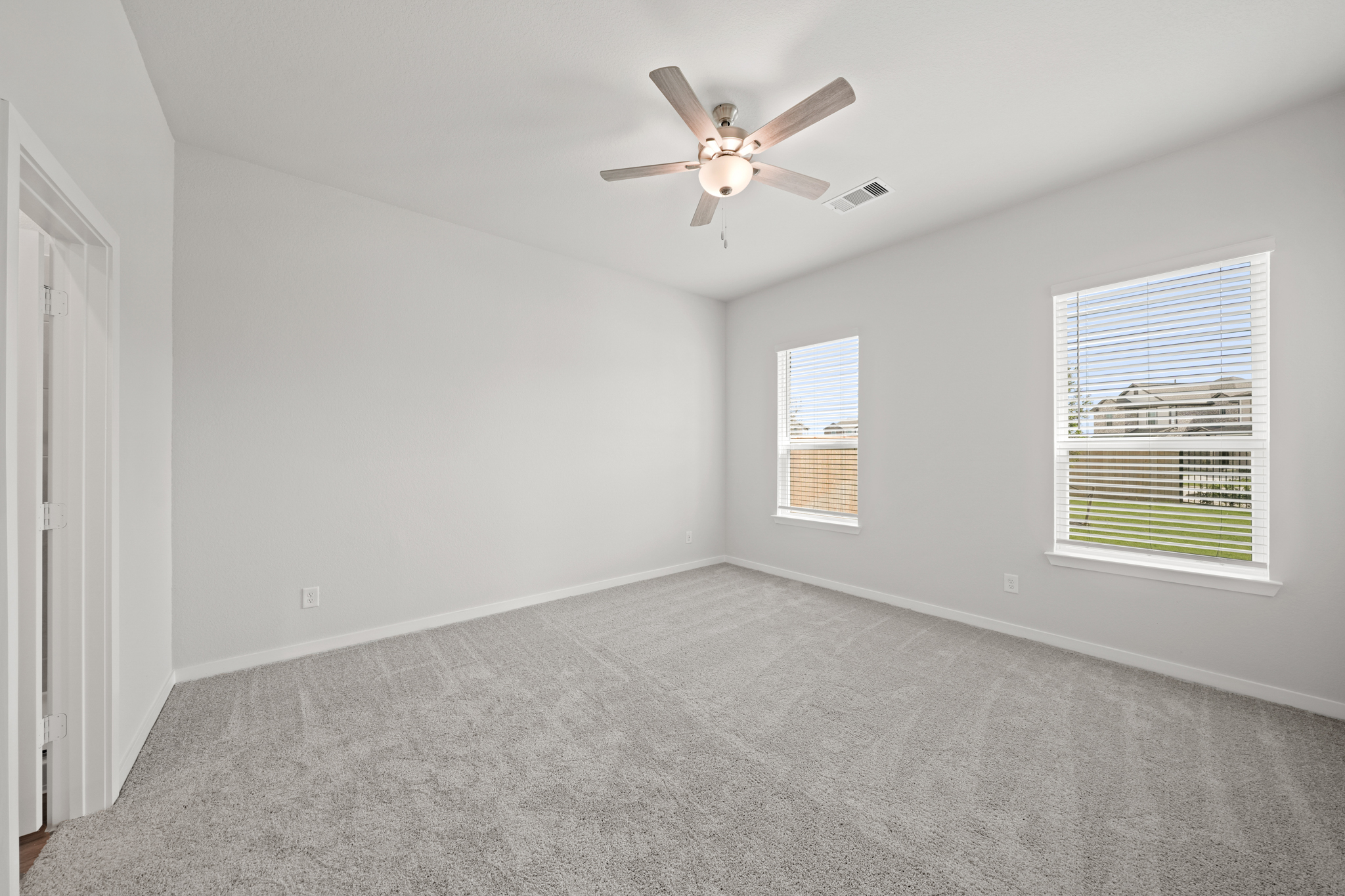 A room with a ceiling fan and a carpet.