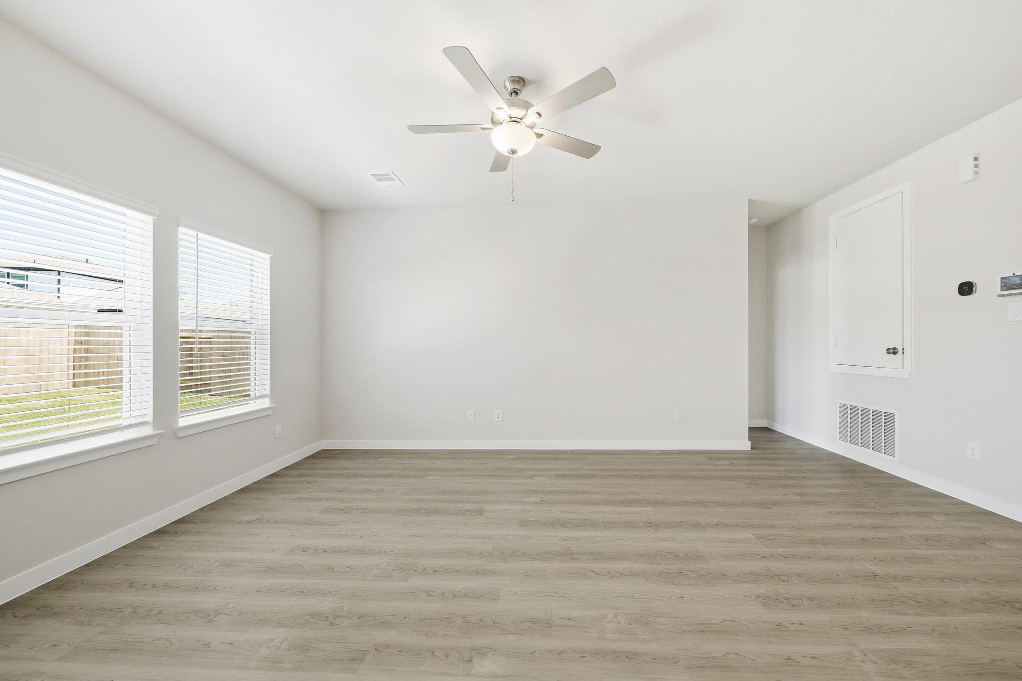 A room with a ceiling fan and a wood floor.