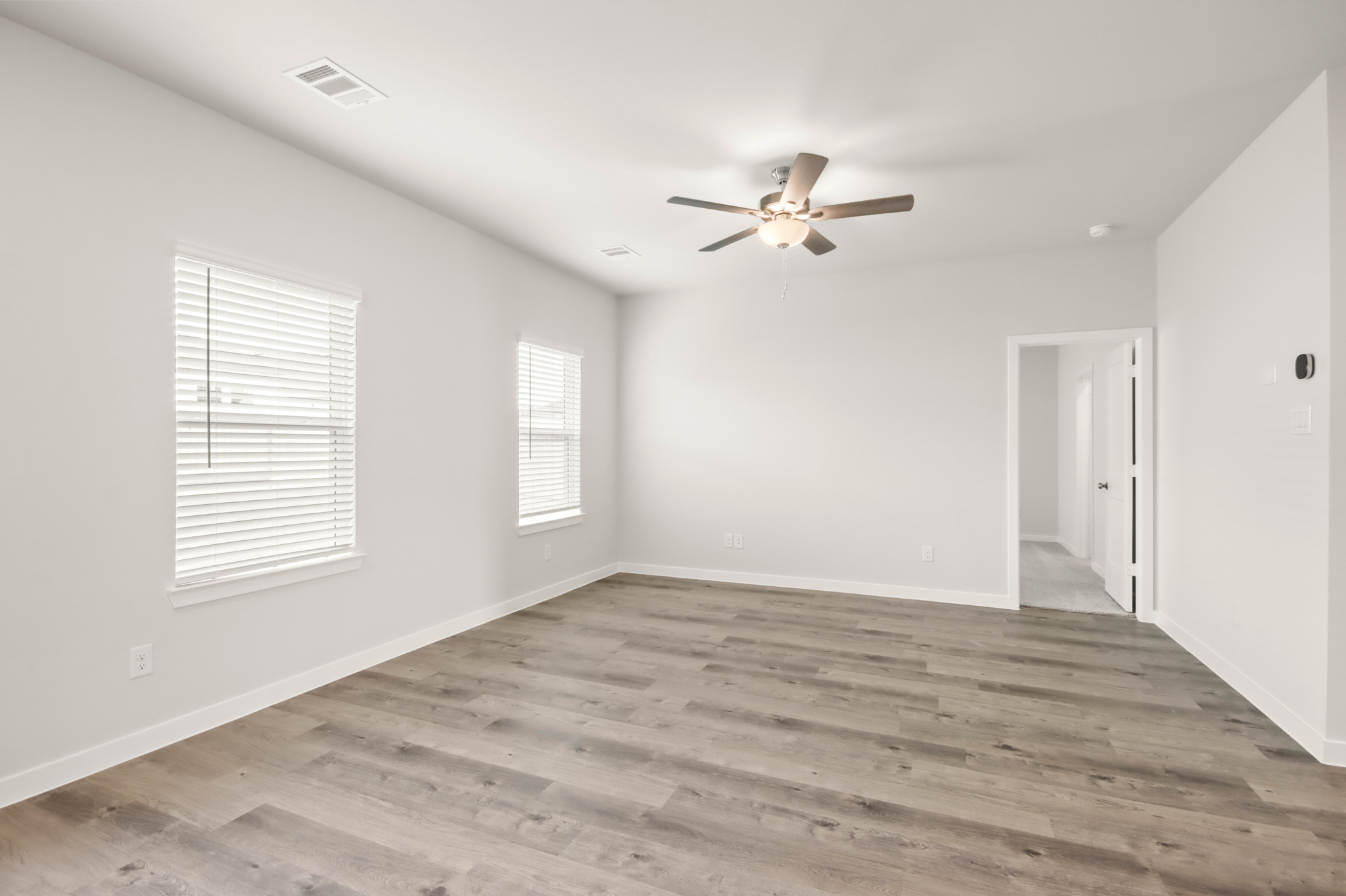 A room with a ceiling fan and wood floor.