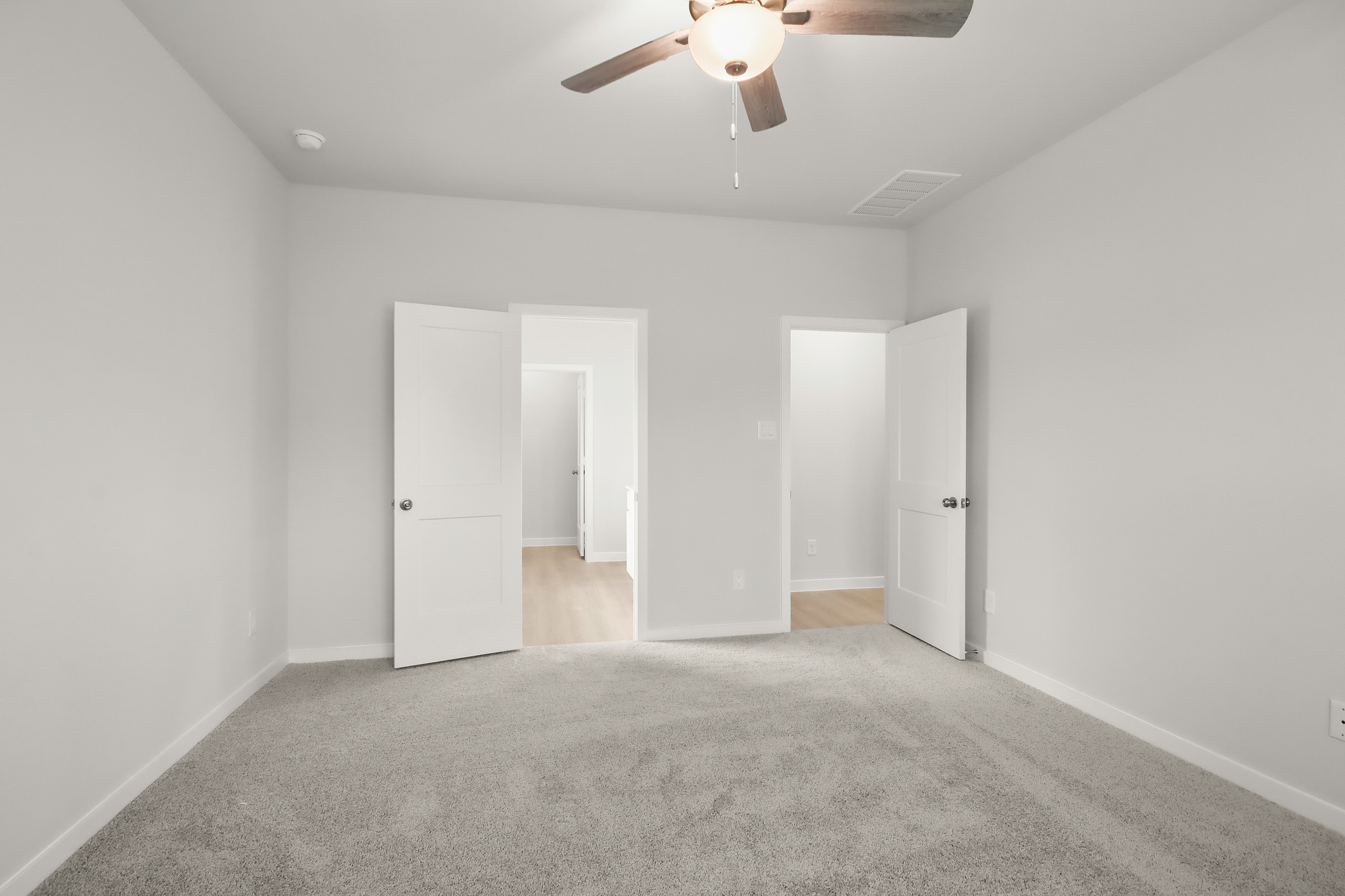A room with white doors and a ceiling fan.