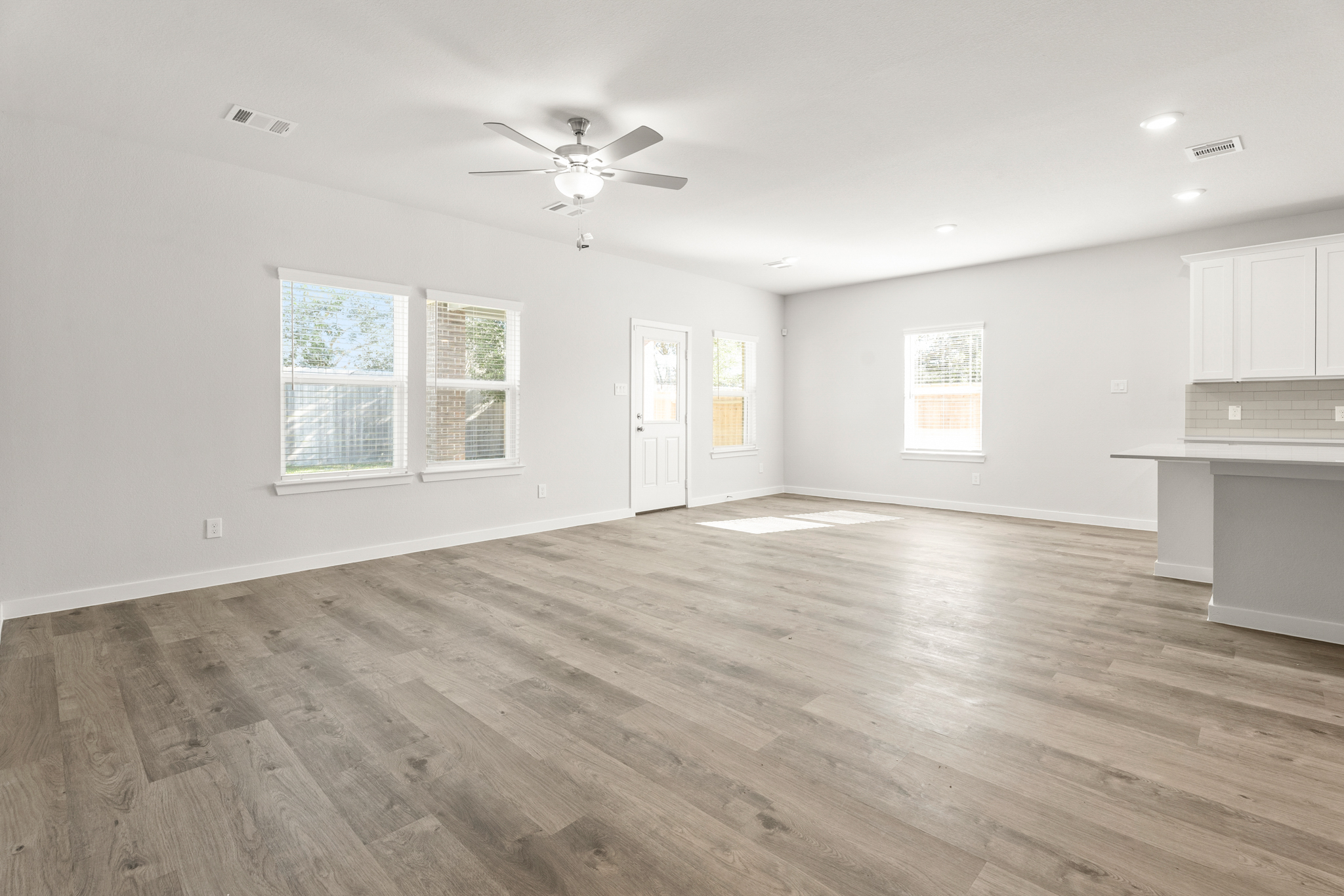 A large empty room with a wood floor and a ceiling fan.