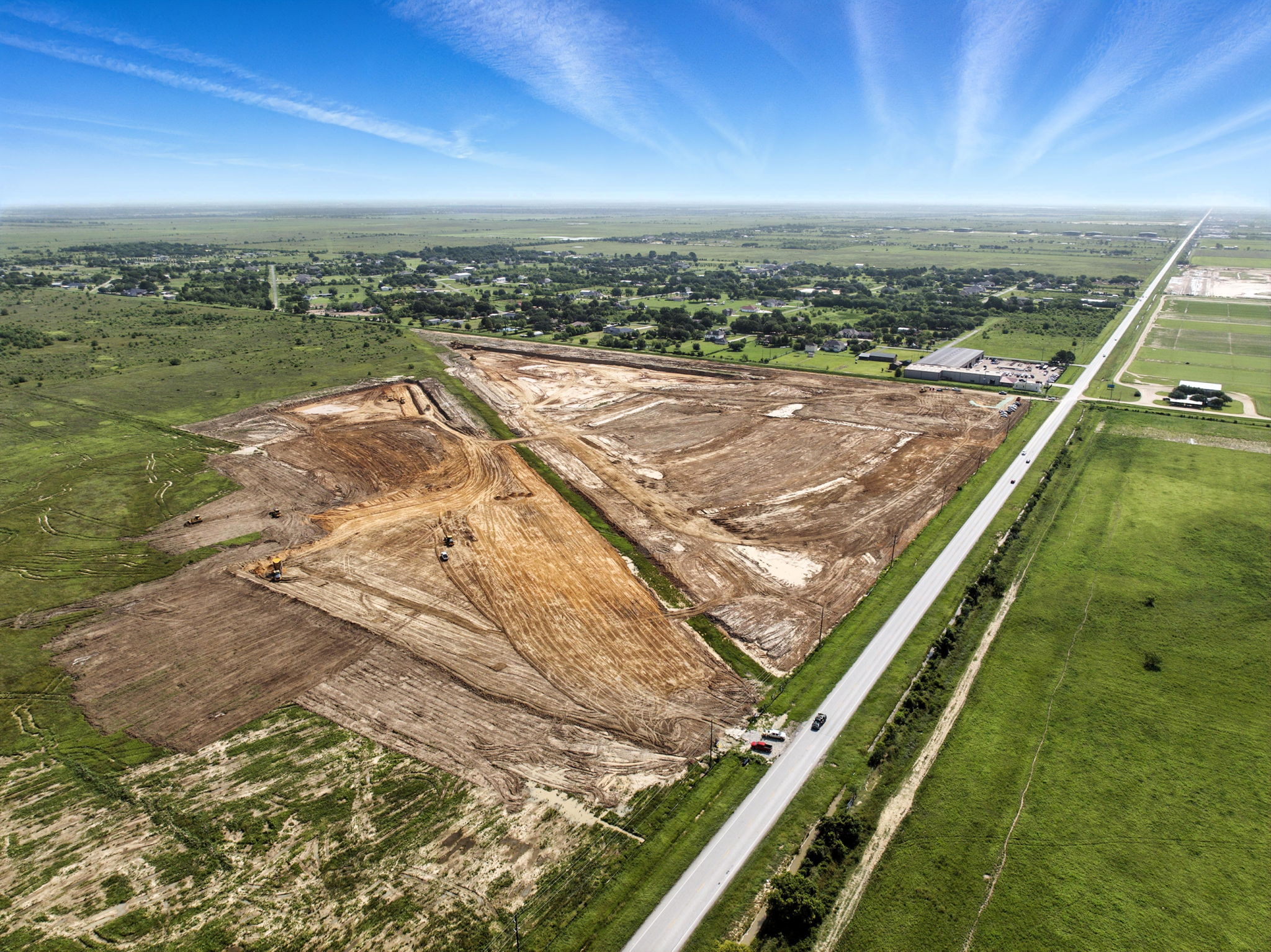 A road with a field and buildings.