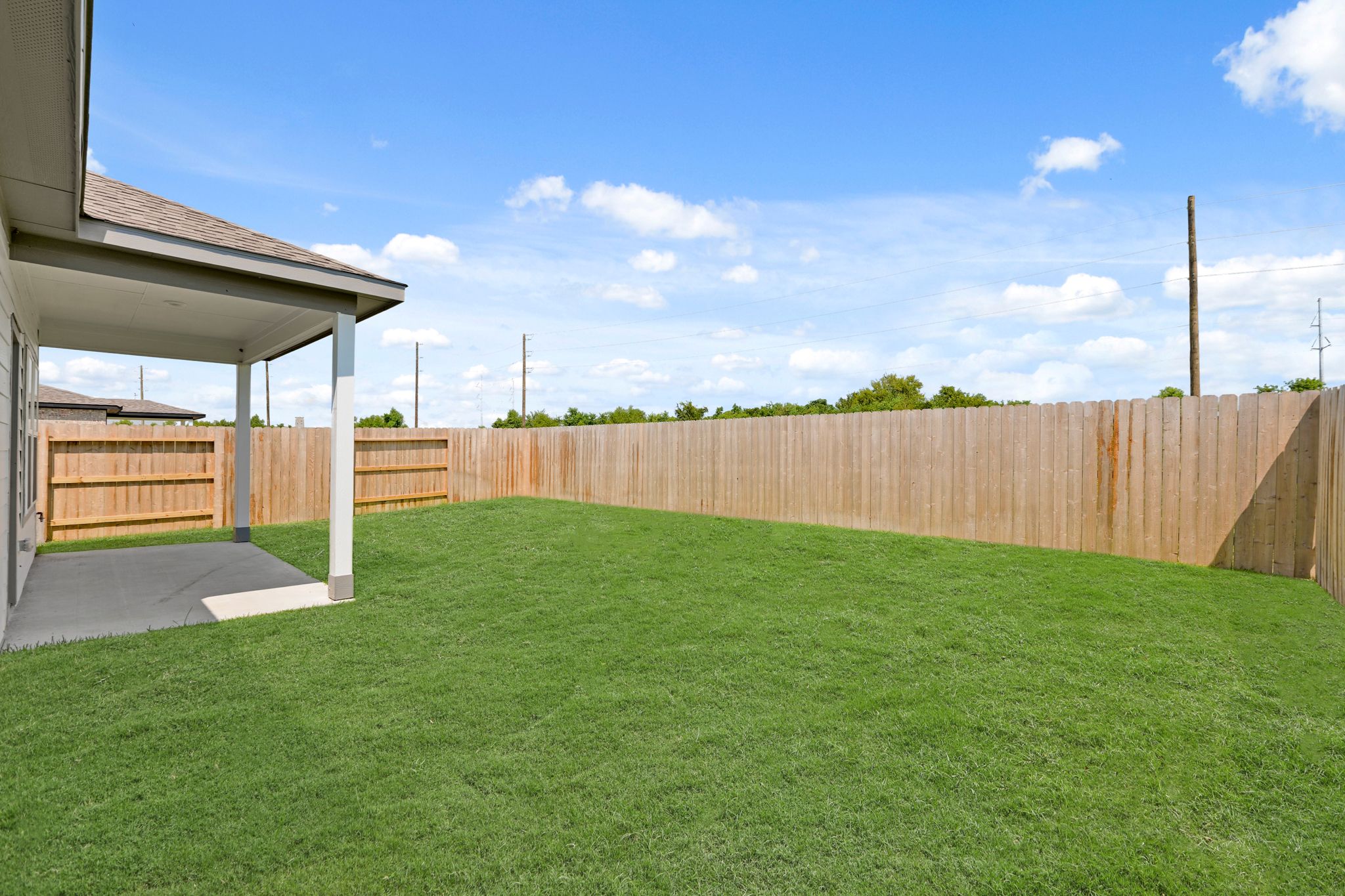 A fenced in yard with a house and a wood fence.