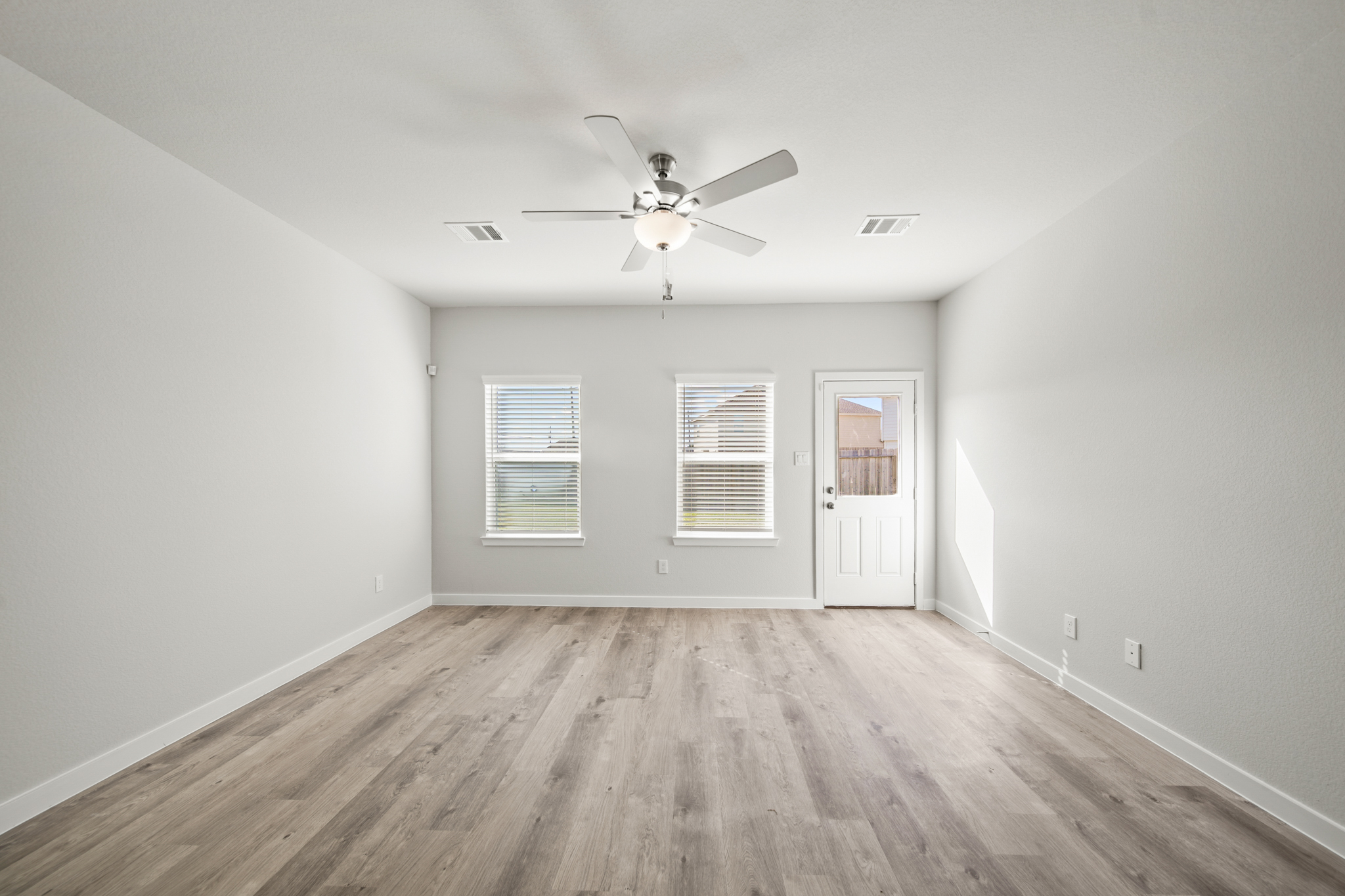 A room with a ceiling fan and a wood floor.
