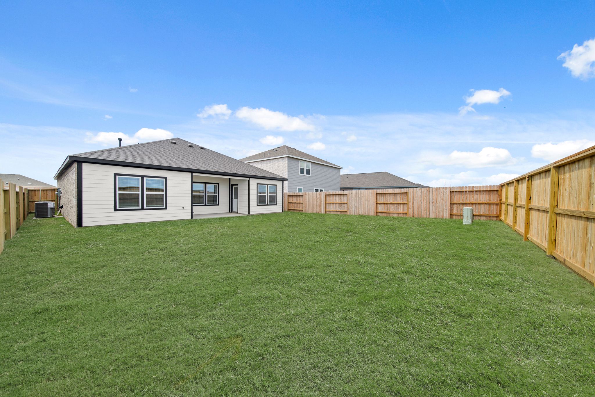 A grassy yard with a fence and a house in the background.