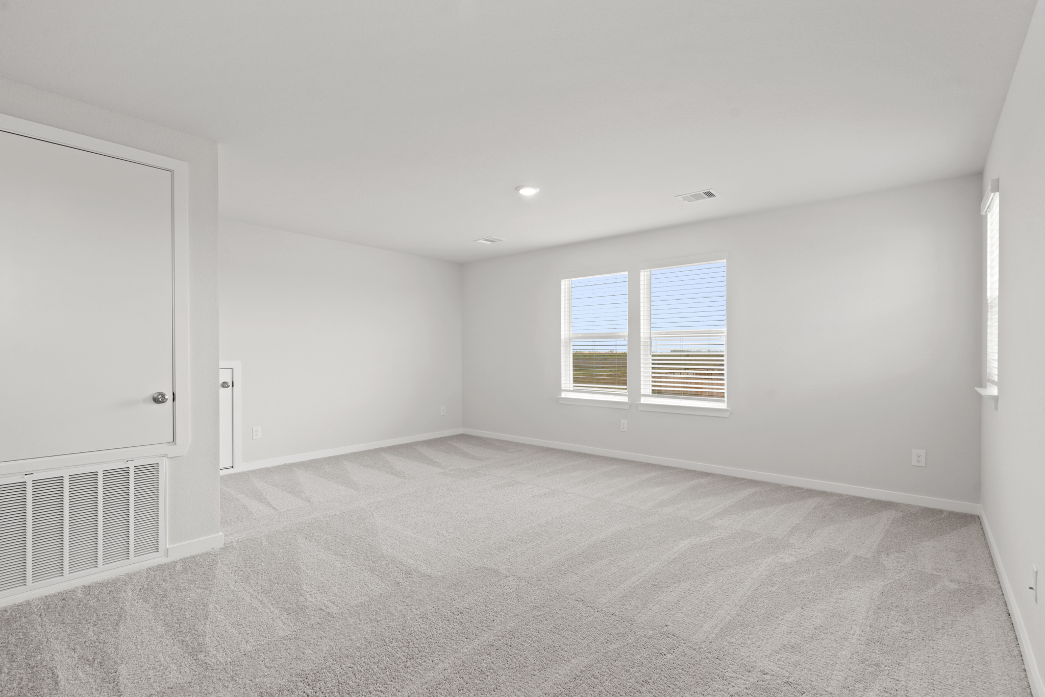 A room with a white carpet and windows.