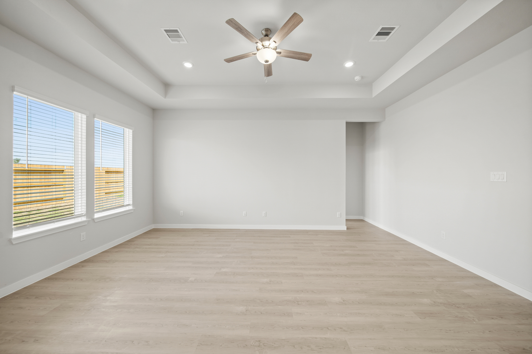 A room with a ceiling fan and a wood floor.