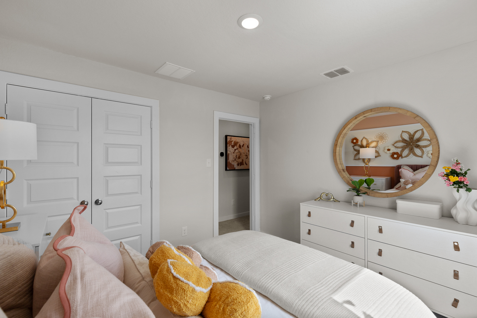 A bedroom with a mirror and a bed.