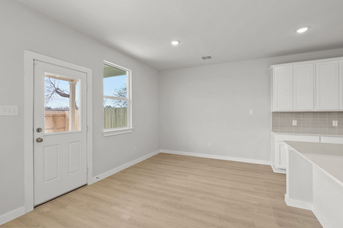 A room with white cabinets and a wood floor.