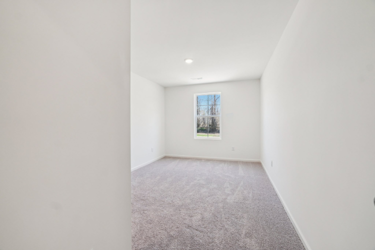 A hallway with a carpet and a window.
