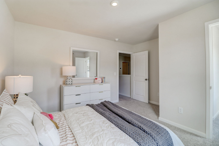 A bedroom with a bed and a mirror.