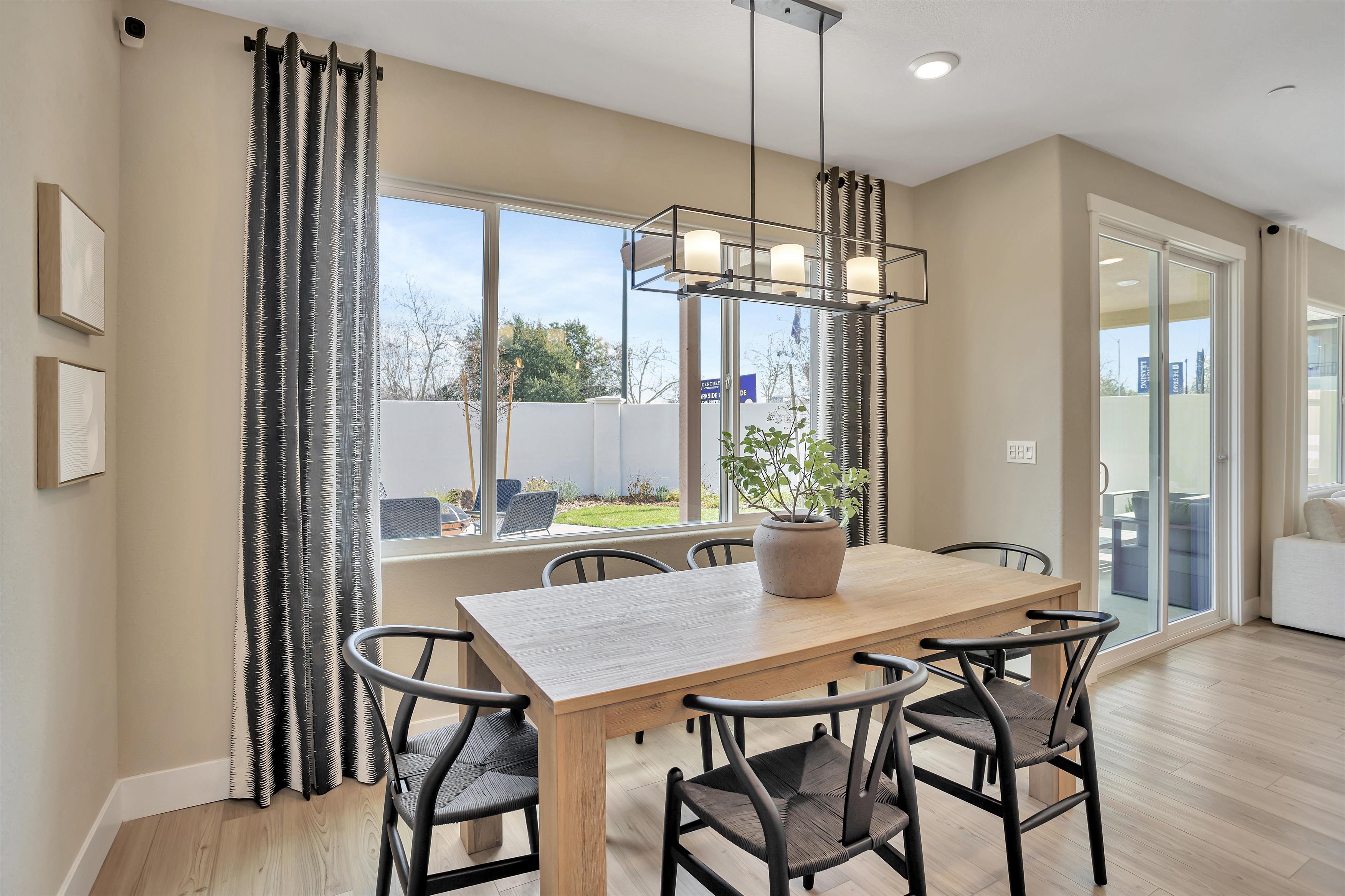 A dining room table with chairs and a chandelier above it.