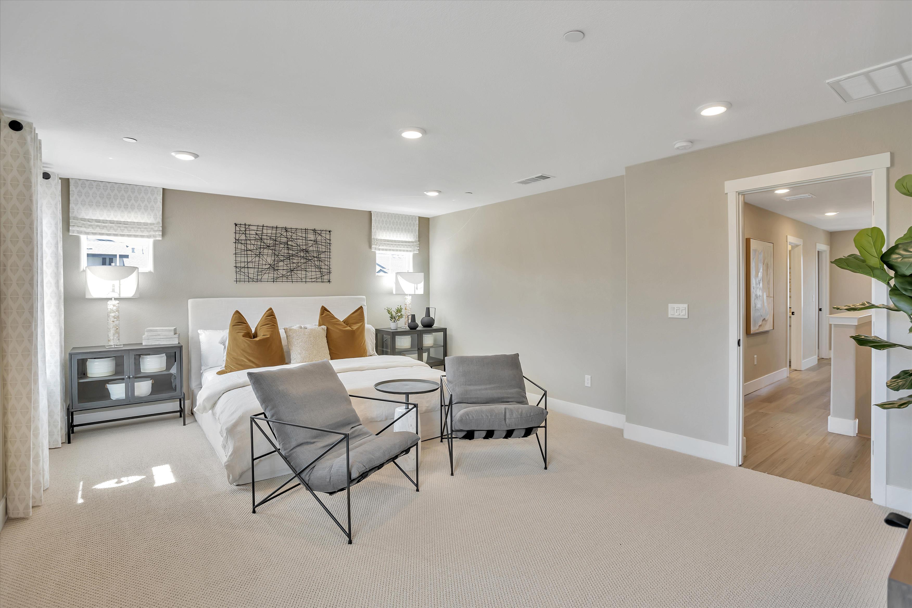 A room with a bed and chairs.