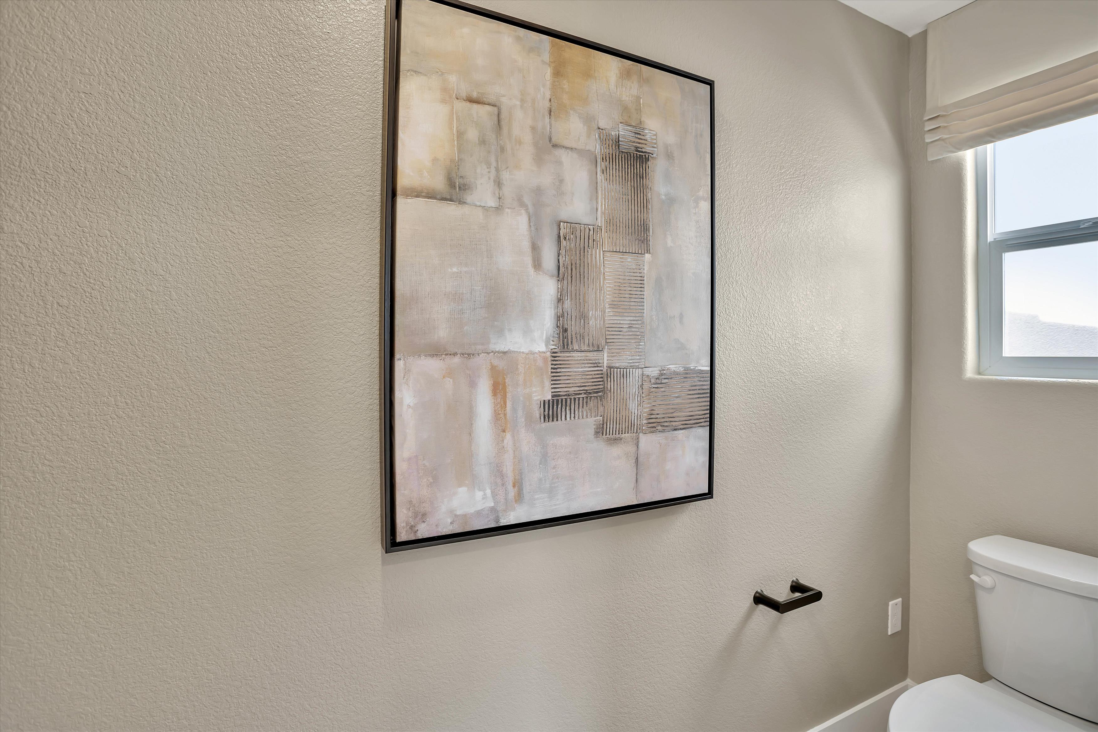 A bathroom with a painting on the wall.